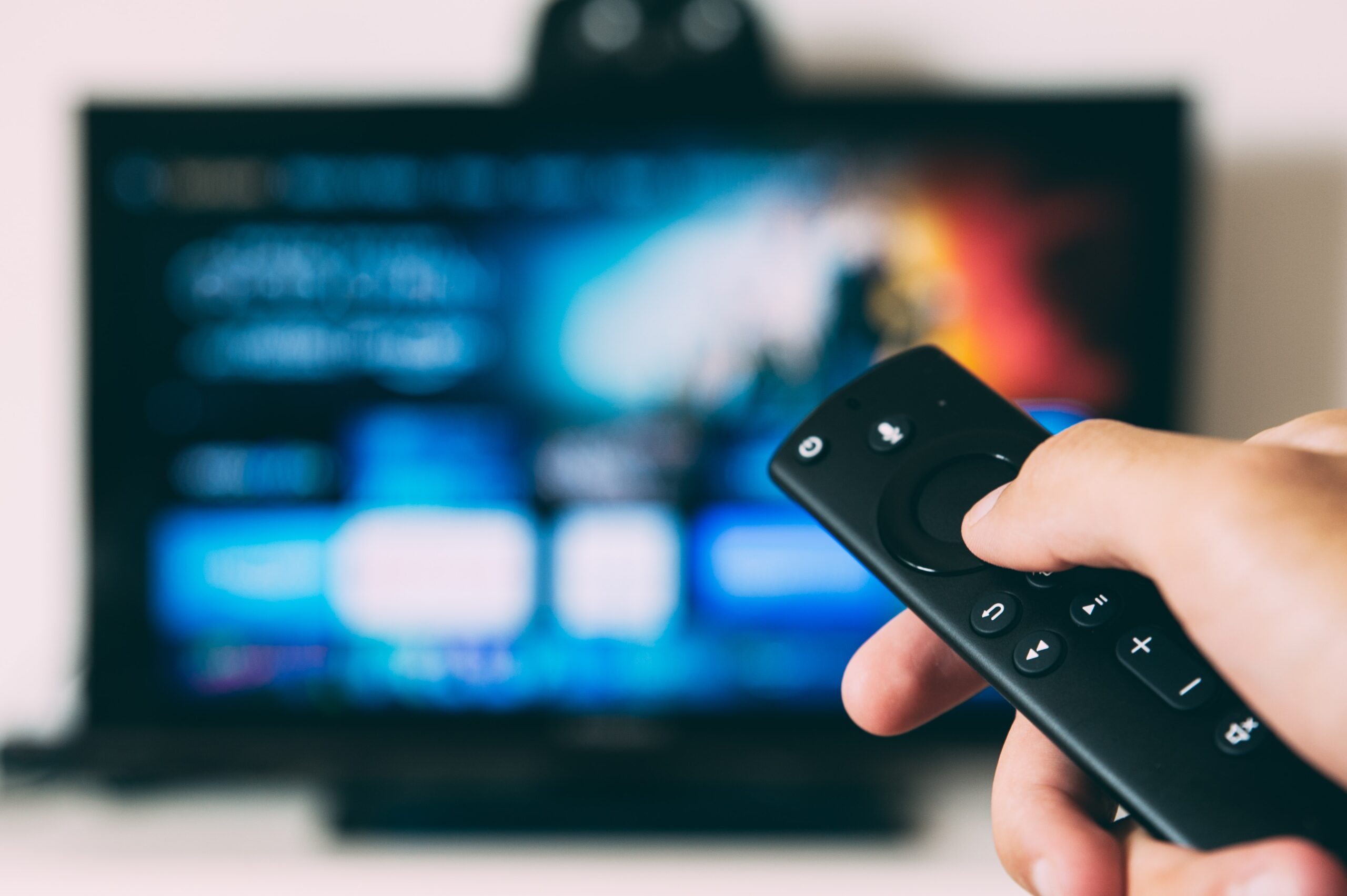 An image of a hand pointing a remote at a TV