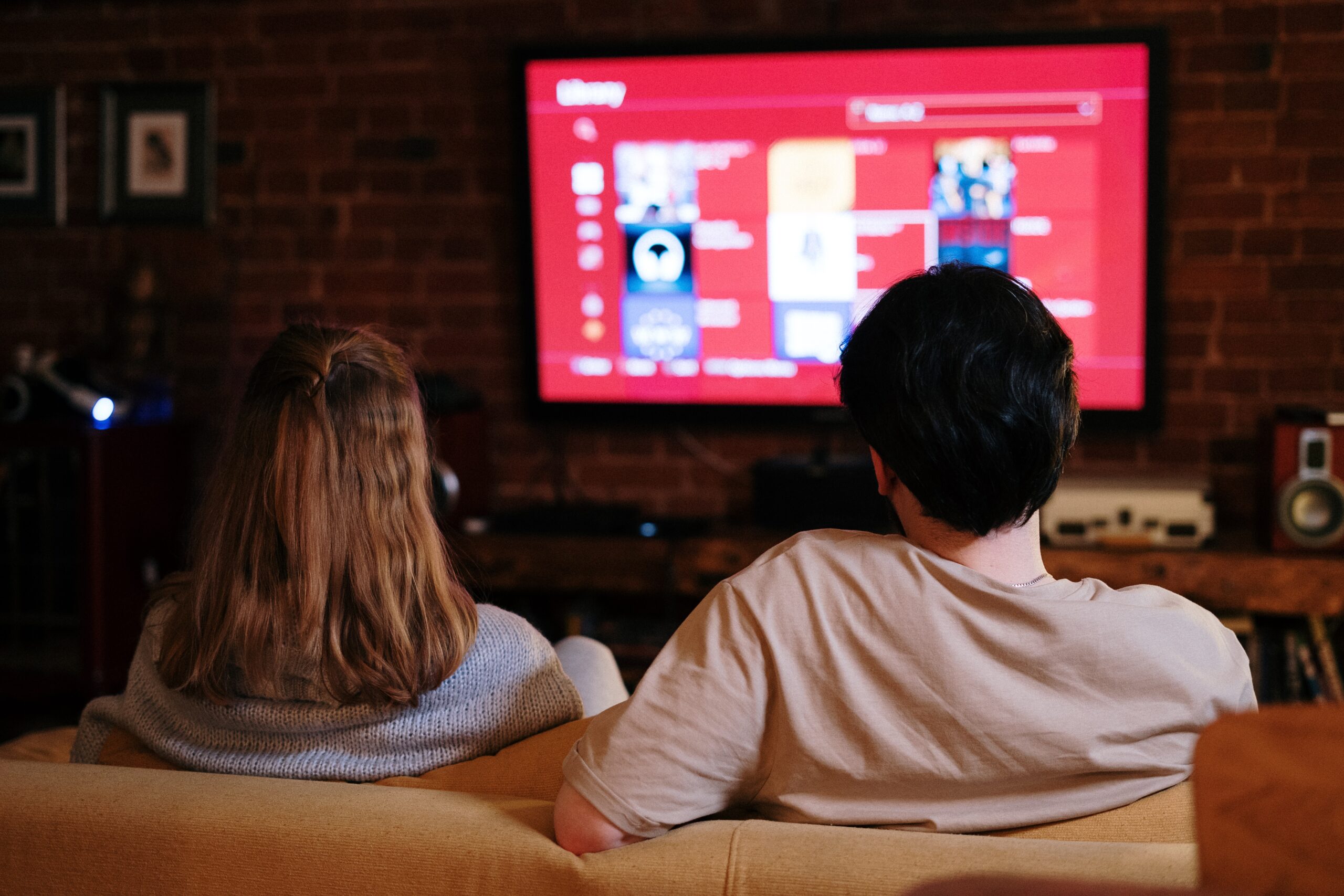 A couple sitting on a couch watching television